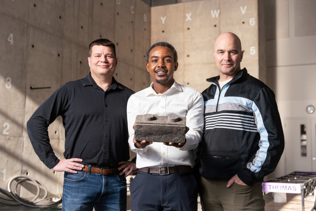 From left, Professor John Wentz, Engineering alumni Brian Osende, and Professor John Ahraham pose for a photo with a prototype of a Brick developed by Osende on December 11, 2024, in St. Paul, in Schoenecker Center.